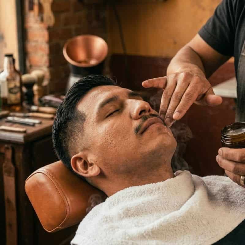 Hombre recibiendo un tratamiento facial relajante en la barberia